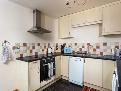 a kitchen with white cabinets and black counter tops at Nectan in St Austell