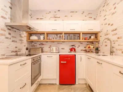 a red refrigerator in a kitchen with white cabinets at Beach Hut in Tintagel