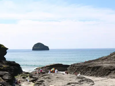 a group of people standing on rocks near the ocean at Beach Hut in Tintagel