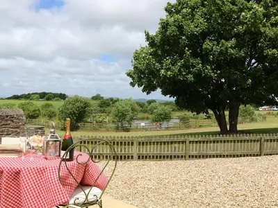 a picnic table with a tree and a fence at Beech Cottage in Truro
