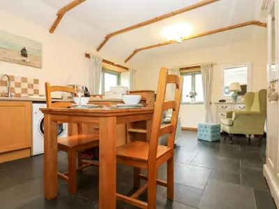 a kitchen and dining room with a wooden table and chairs at Beech Cottage in Truro