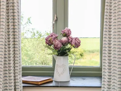 a vase filled with purple flowers sitting on a window sill at Beech Cottage in Truro
