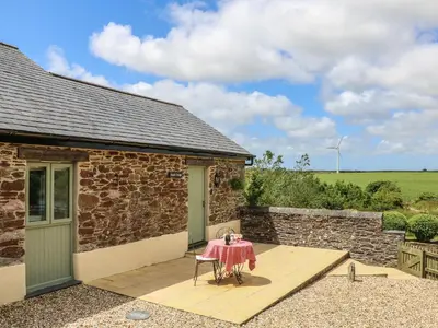 a table and chairs on a patio outside of a stone building at Beech Cottage in Truro