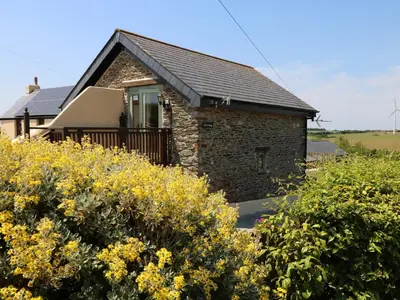 a stone house with yellow flowers in front of it at Oak Cottage in Truro