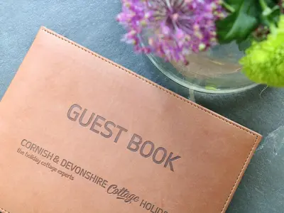 a guest book sitting next to a vase of flowers at Oak Cottage in Truro