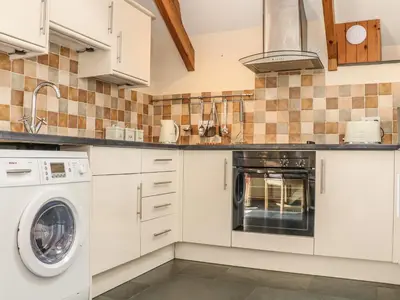 a kitchen with white cabinets and a washer and dryer at Oak Cottage in Truro