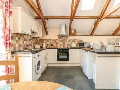 a kitchen with white cabinets and a washer and dryer at Oak Cottage in Truro