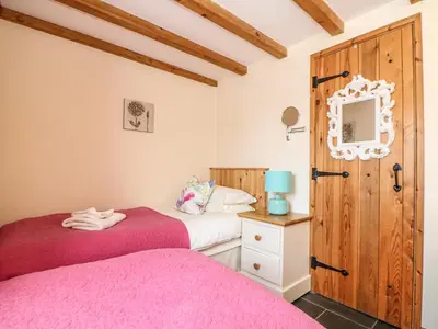 a bedroom with two beds and a mirror at Oak Cottage in Truro