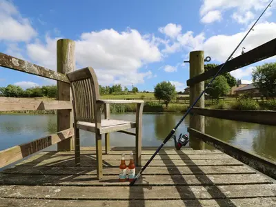 a chair and two bottles of beer on a dock at Oak Cottage in Truro