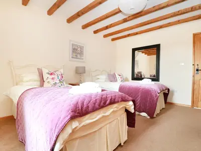a bedroom with two beds and a mirror at Hawthorn Cottage in Truro