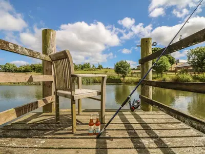 a chair and two bottles of beer on a dock at Hawthorn Cottage in Truro