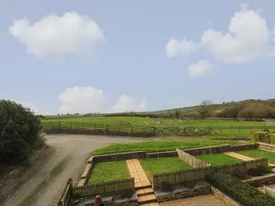 a farm with sheep in a field with a dirt road at Hawthorn Cottage in Truro