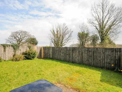 a backyard with a fence and a skateboard in the grass at Barn Owl Cottage in Launceston