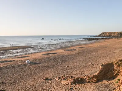 a beach with a bottle on the sand at Barn Owl Cottage in Launceston