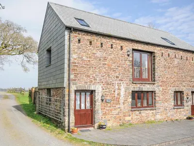 a brick building with a red door and windows at Barn Owl Cottage in Launceston