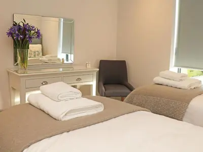 a bedroom with two beds and a desk with a mirror at Little Fistral in Newquay