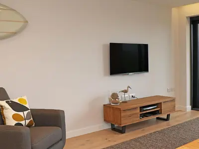 a living room with a tv on a white wall at Little Fistral in Newquay