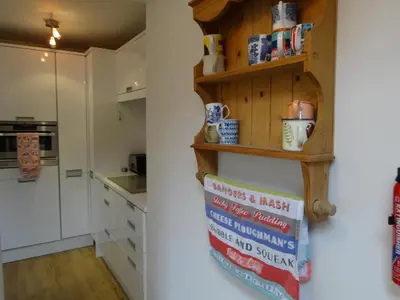a kitchen with white cabinets and a shelf on the wall at Heatherdale in Tintagel