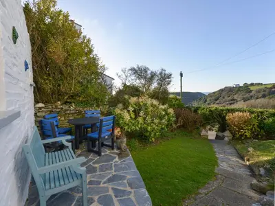 a patio with blue chairs and a table in a yard at Heatherdale in Tintagel