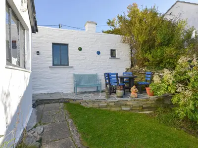 a patio with two chairs and a blue bench at Heatherdale in Tintagel