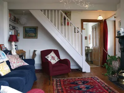 a living room with a blue couch and a staircase at Heatherdale in Tintagel