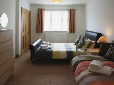 a bedroom with a bed and a couch and a window at Seagulls Perch in Mawgan Porth