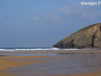 a beach with a large rock in the ocean at Seagulls Perch in Mawgan Porth