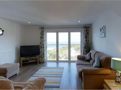 a living room with a couch and a television at Seagulls Perch in Mawgan Porth