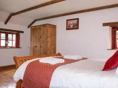 a bedroom with two beds and a wooden cabinet at Samuels Cottage in Lanreath