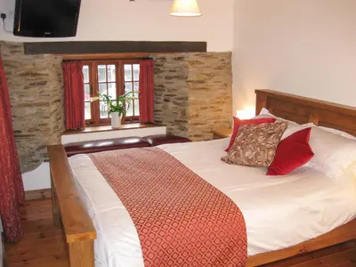 a bedroom with a large bed with red pillows at Samuels Cottage in Lanreath