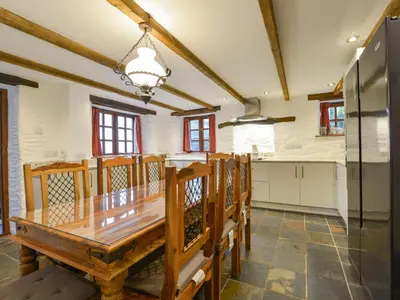 a kitchen with a wooden table and a refrigerator at Samuels Cottage in Lanreath