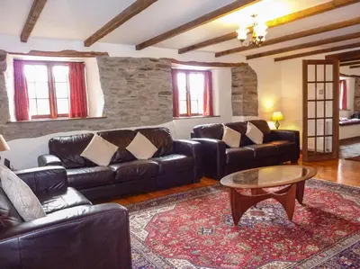 a living room with leather couches and a coffee table at Samuels Cottage in Lanreath