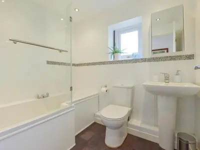 a white bathroom with a toilet and a sink at Hideaway Barn in Charlestown