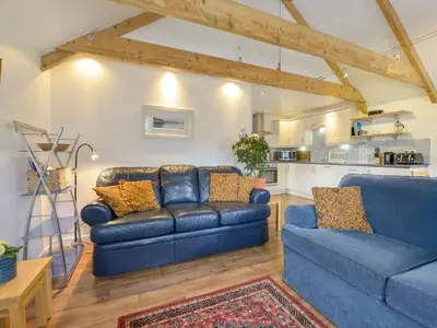 a living room with two blue couches and a kitchen at Hideaway Barn in Charlestown