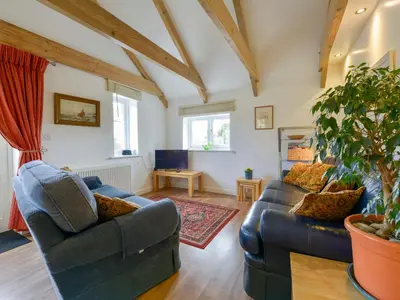 a living room with two couches and a tv at Hideaway Barn in Charlestown