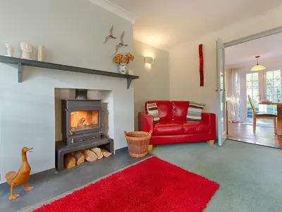 a living room with a red couch and a fireplace at Orchard Lodge in Boscastle