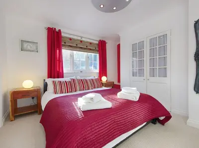 a bedroom with two beds with red curtains at Orchard Lodge in Boscastle