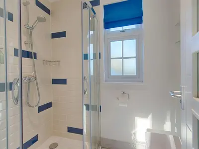 a bathroom with a shower with a window and a sink at Orchard Lodge in Boscastle