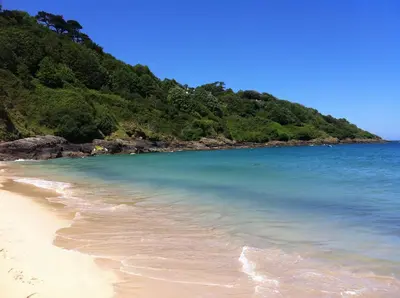 a beach with clear blue water and a mountain at Seaside Bungalow in St Ives