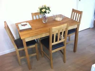 a wooden table with chairs and a vase of flowers on it at Seaside Bungalow in St Ives