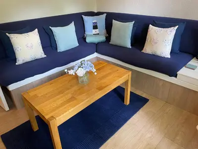 a blue couch with pillows and a wooden coffee table at Seaside Bungalow in St Ives