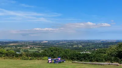 two colorful benches sitting on top of a hill at Wesley House Holidays - Choice of 2 Quirky Cottages in 4 private acres in Redruth