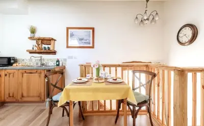 a kitchen with a table with chairs and a clock on the wall at Wesley House Holidays - Choice of 2 Quirky Cottages in 4 private acres in Redruth