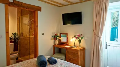 a bedroom with a bed and a television on the wall at Wesley House Holidays - Choice of 2 Quirky Cottages in 4 private acres in Redruth