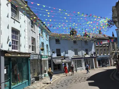 people walking down a street with flags and buildings at No.10 Falmouth - 2 minutes walk to the beach in Falmouth