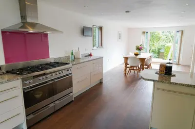 a kitchen with a stove and a dining table at No.10 Falmouth - 2 minutes walk to the beach in Falmouth
