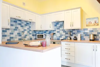 a kitchen with white cabinets and blue tiles at 3 The Old School House in St. Agnes