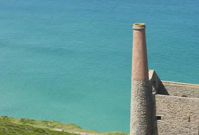a stone tower on top of a hill next to the water at Amaroo in St. Agnes