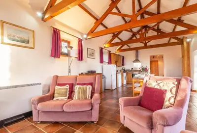 a living room with two chairs and a kitchen at Church Close Cottage in Gwennap