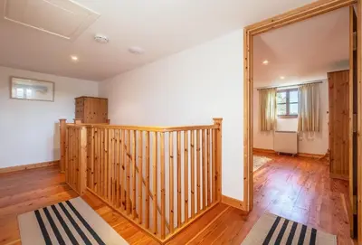 a room with a wooden staircase and a mirror at Church Close Cottage in Gwennap